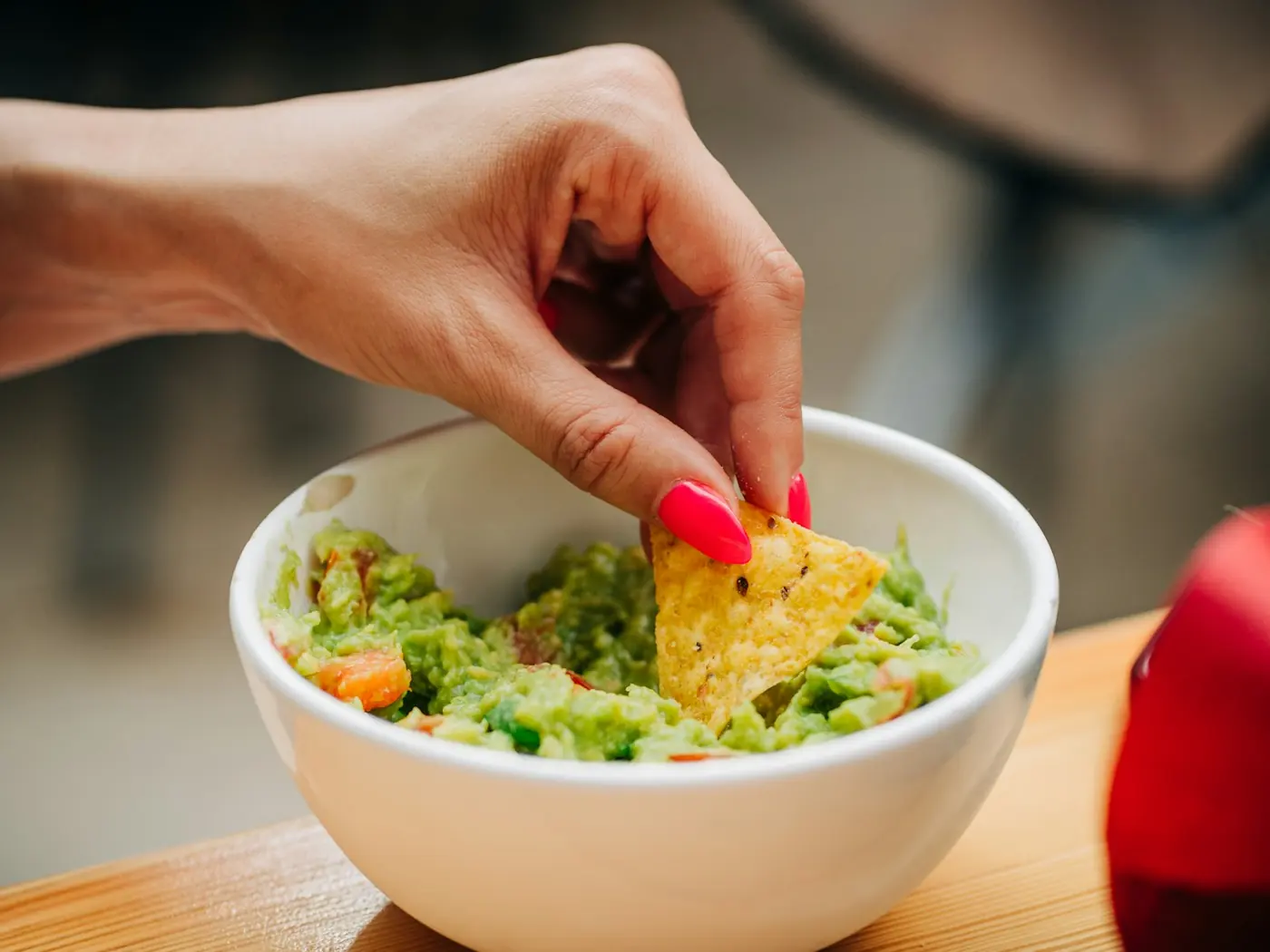 A tortilla chip dipped into a bowl of guacamole