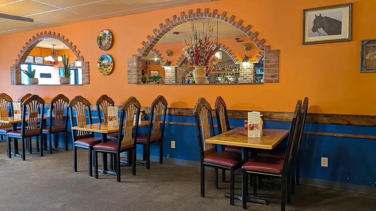 Blue wainscot and orange wall with brick-framed mirrors, painted plates and a set table