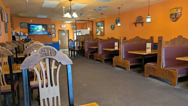 A carved wood chair at the end of a row of booths under hanging lanterns