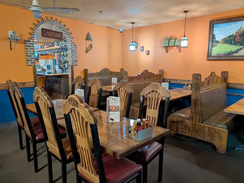 The CANTINA brick arch in the orange wall, with a carved wood booth and chairs beside it