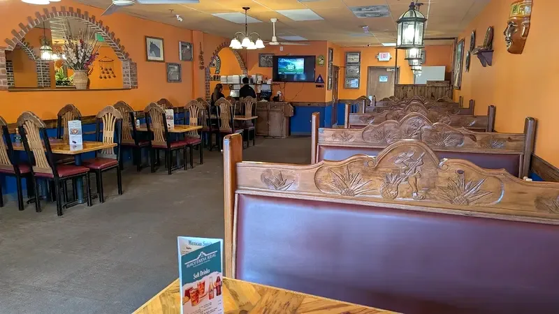 A carved leather booth in the foreground, with more booths running down the dining room
