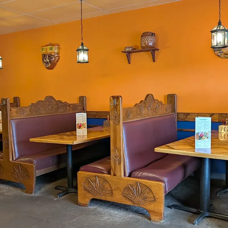 Booth tables with carved high backs beside the orange wall