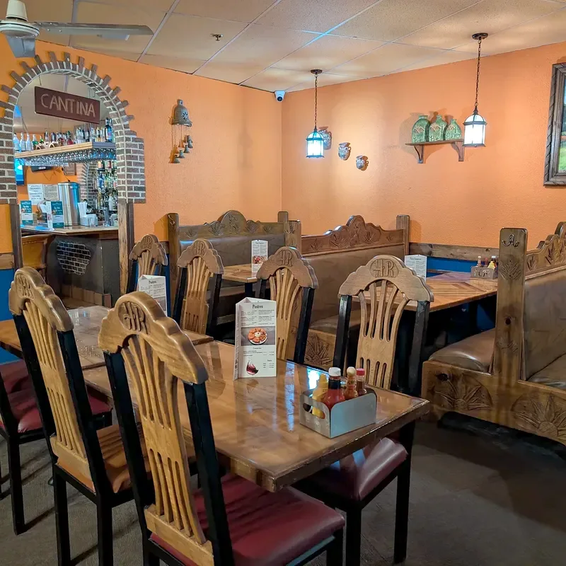 A carved wood booth and chairs, with the CANTINA arch in the corner behind